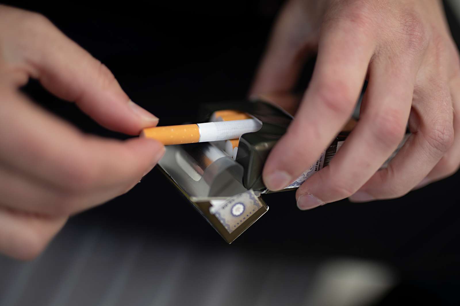 Billede af et par hænder med en cigaretpakke.